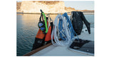 Freediving equipment including a mask fins, and floatline on a boat with water and rocks in the background.